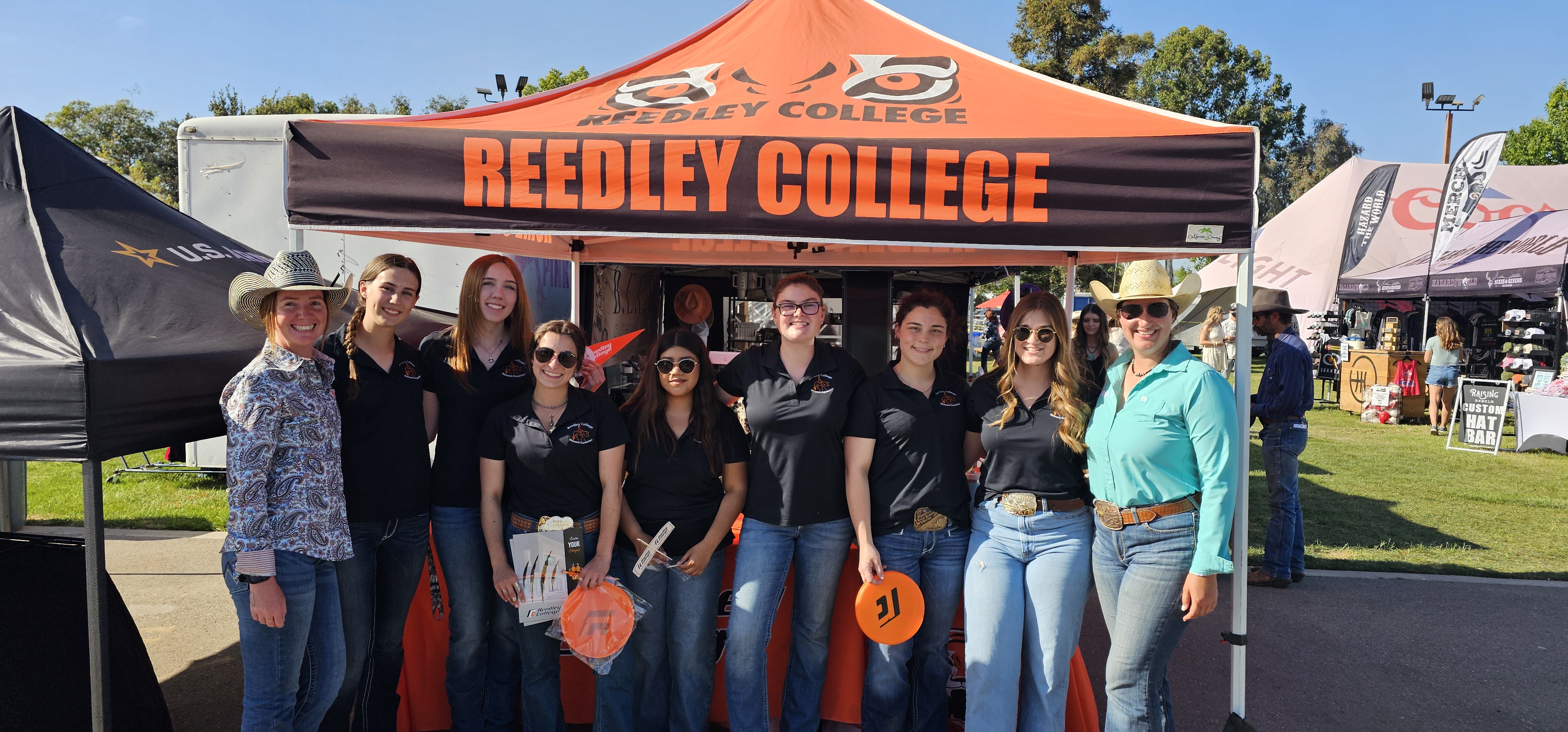 Reedley College Students in front of a Reedley College booth at the Clovis Rodeo.